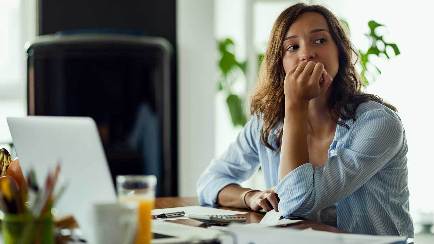 woman sitting at work desk looking anxious